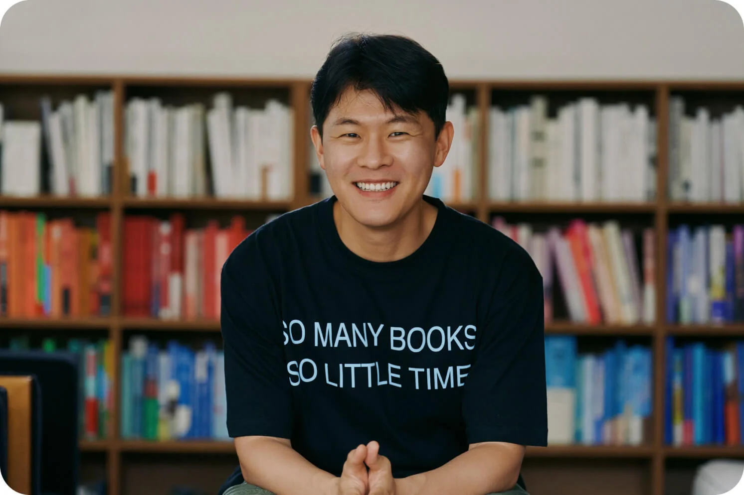 많은 책들에 둘러 싸여 인터뷰를 하며 활짝 웃고 있는 태재 작가
